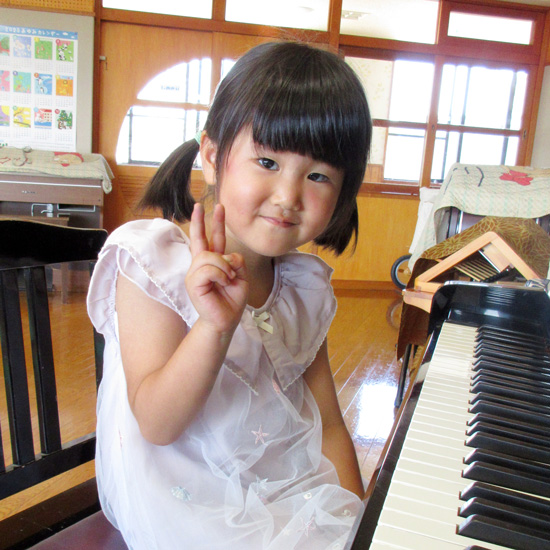 ピアノの前で少し恥ずかしそうにピースする幼児の生徒さんの写真 / みほピアノ教室（相模原市南区）